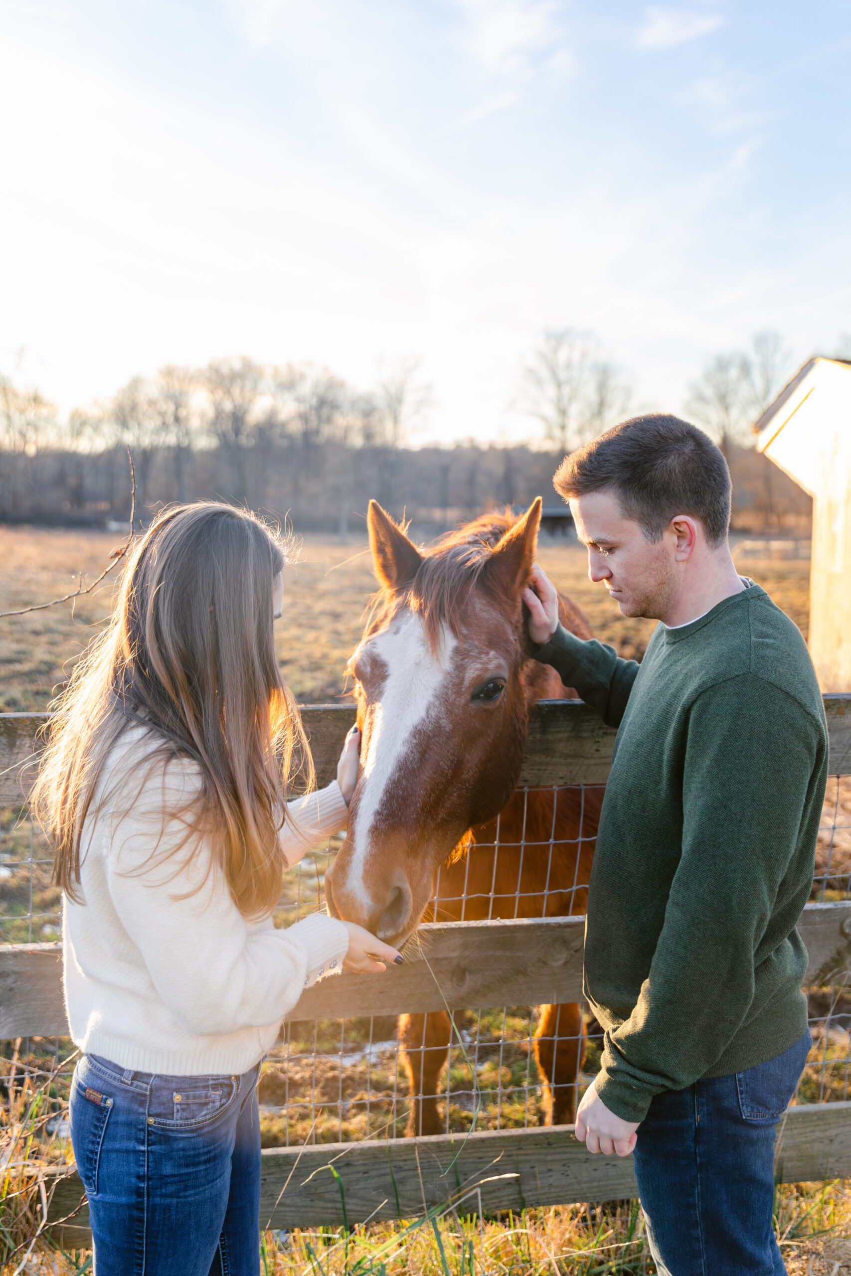 Couple petting a horse on a farm