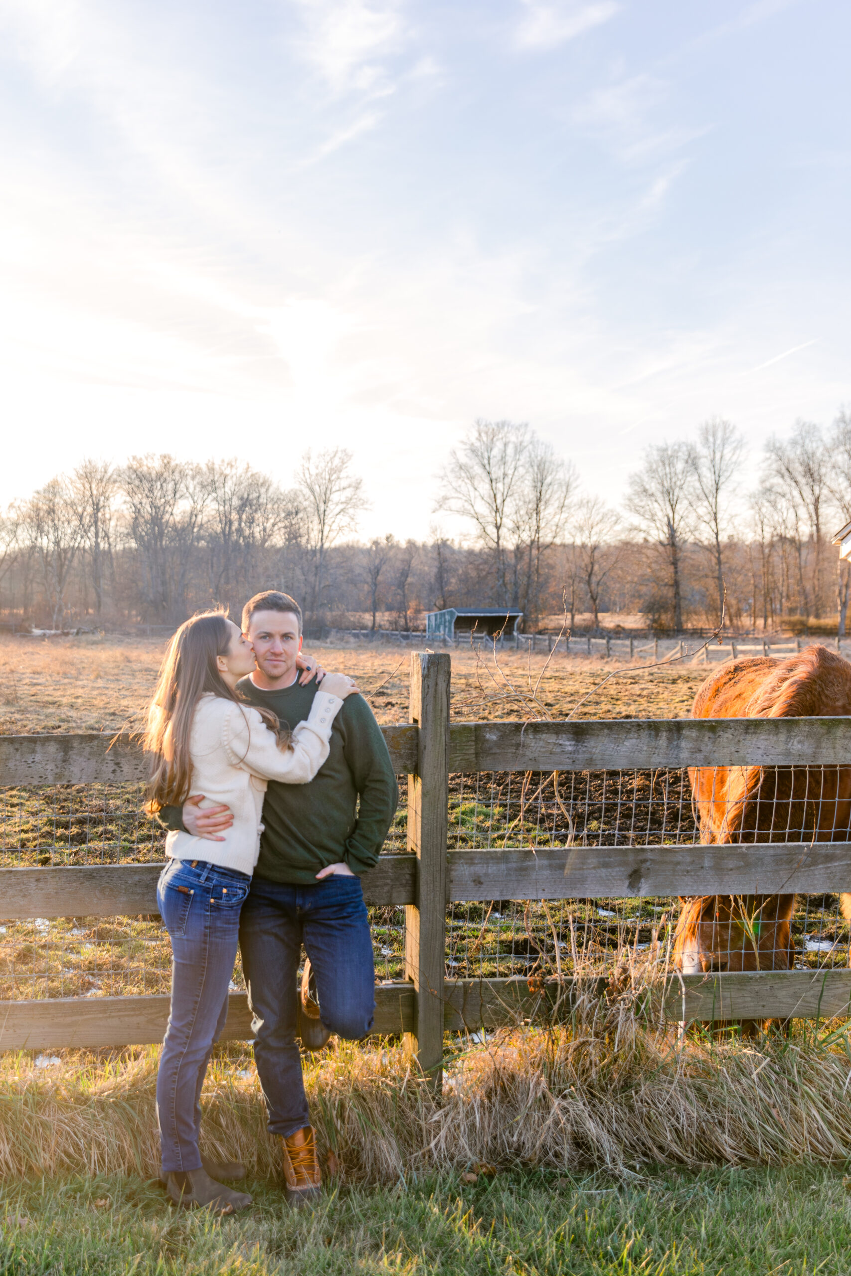 Couple leaning on a fence with a horse on a farm