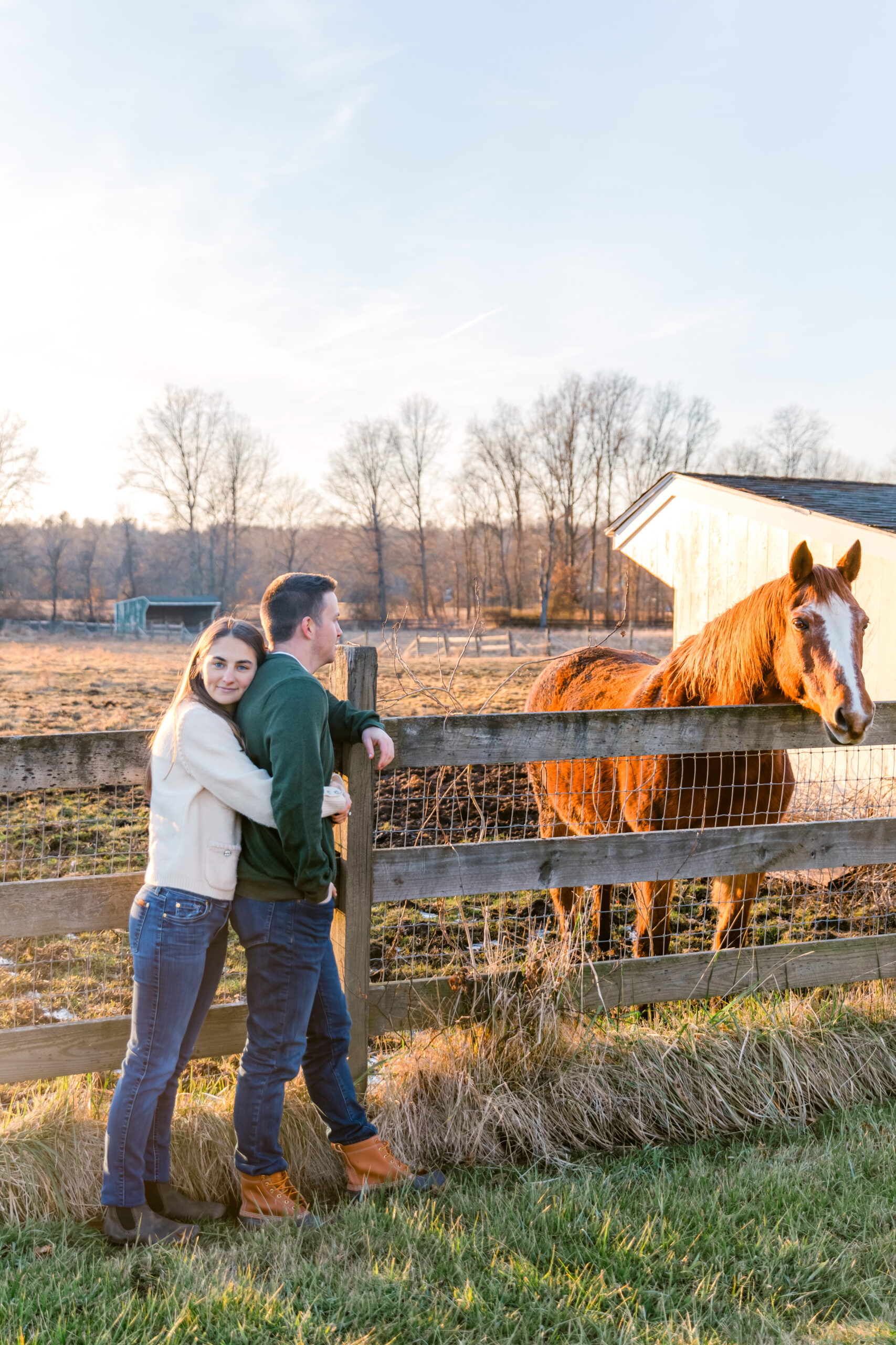 Couple leaning on a fence with a horse on a farm