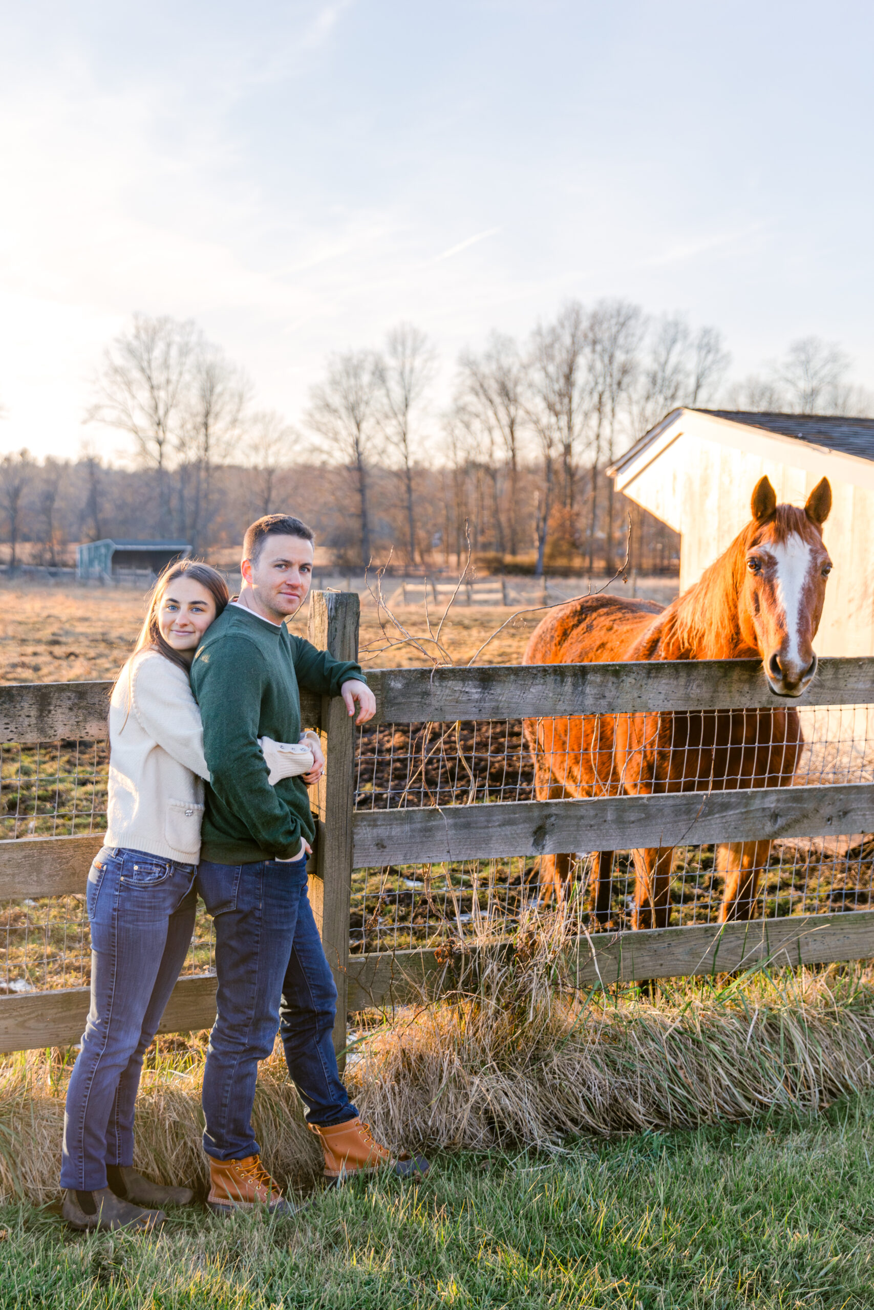 Couple leaning on a fence with a horse on a farm