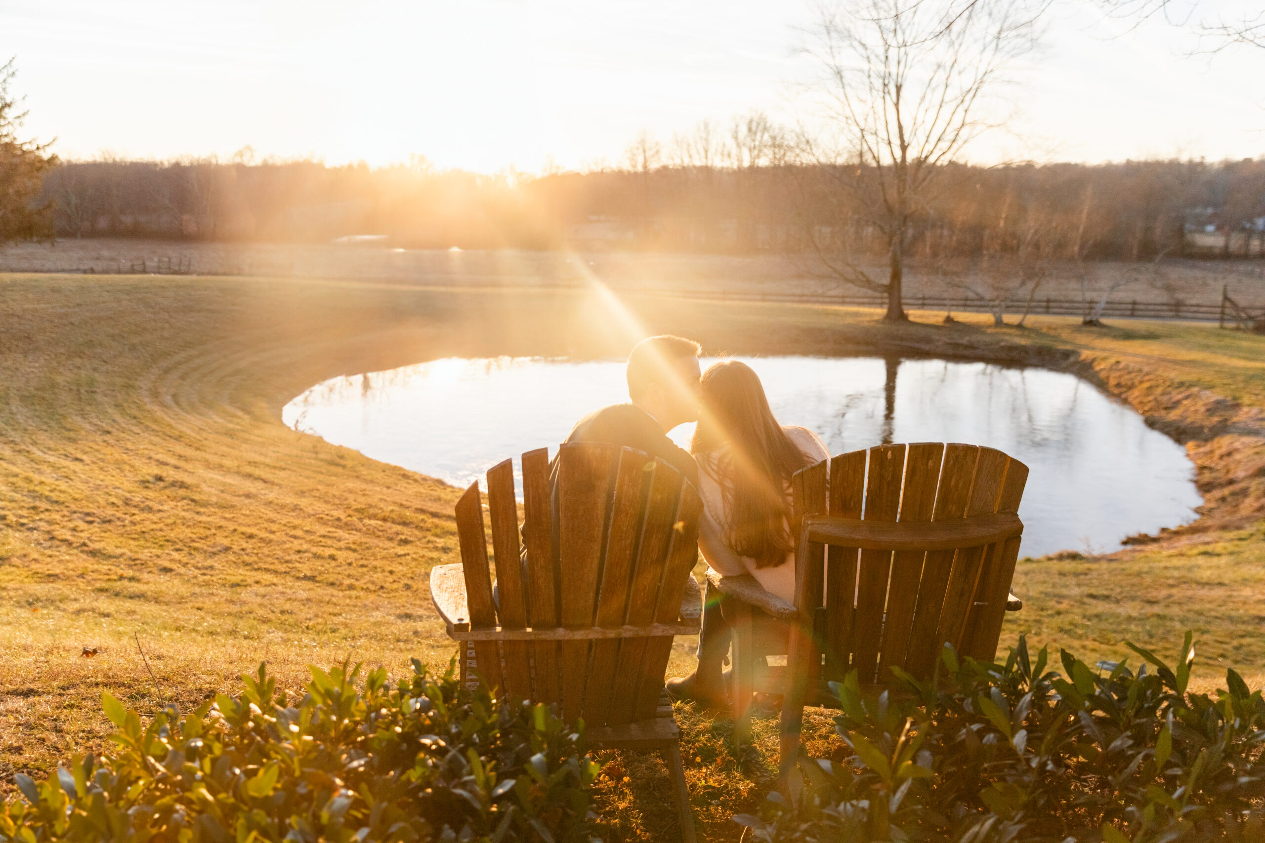 Couple sitting on Adirondack chairs over looking pond