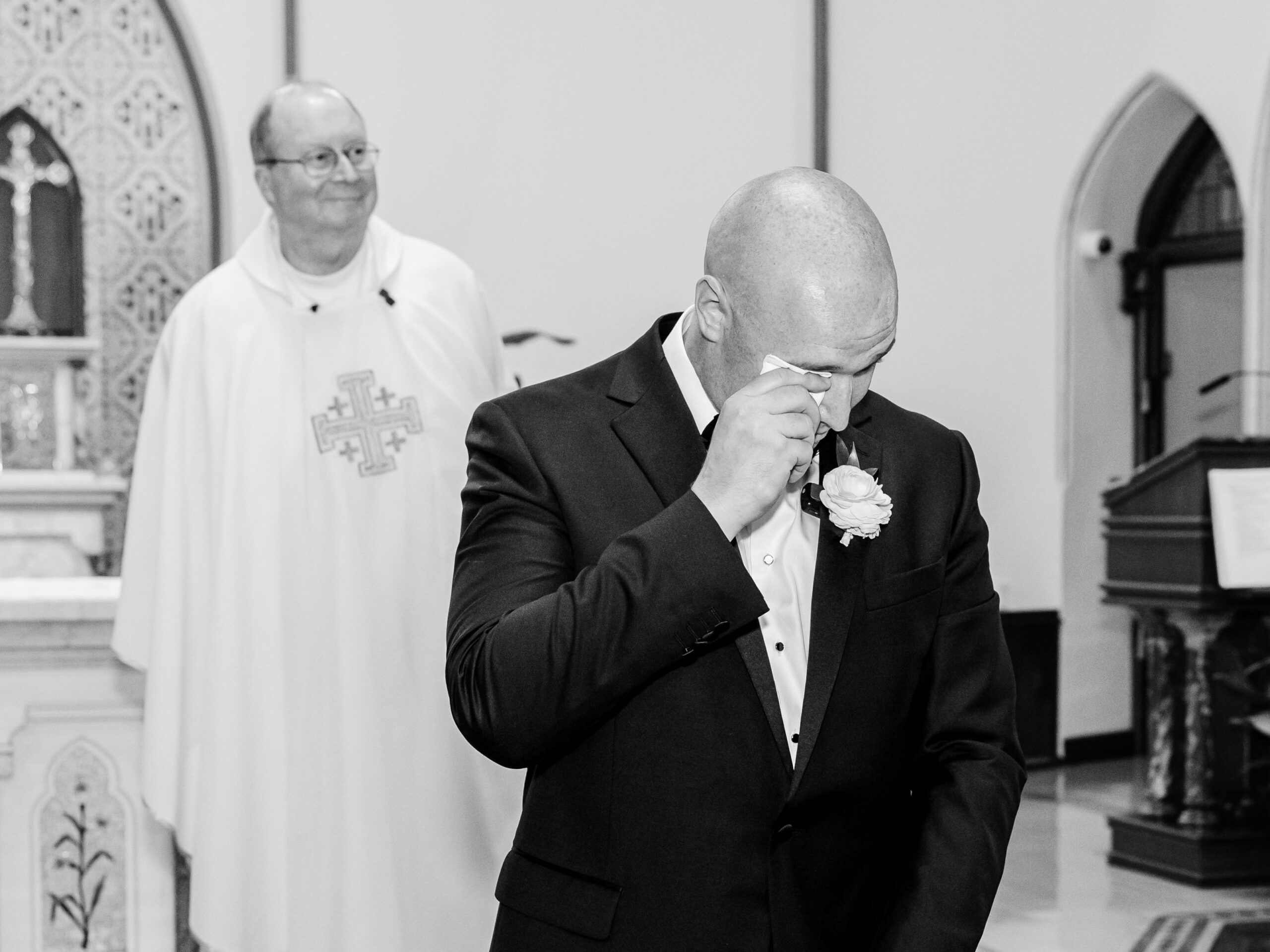 black and white photo of groom crying as bride walks down the aisle