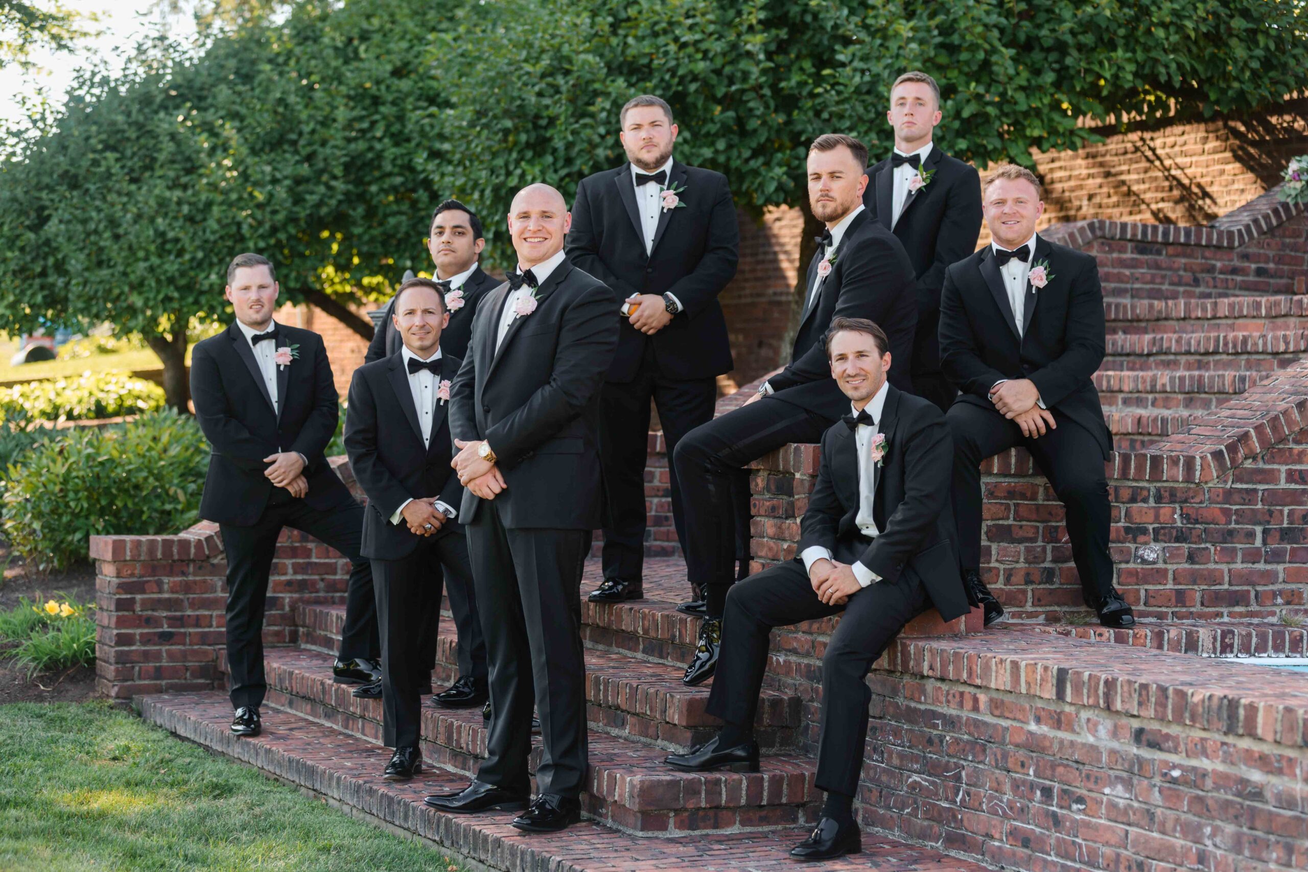groomsmen pose in black suits on stairs